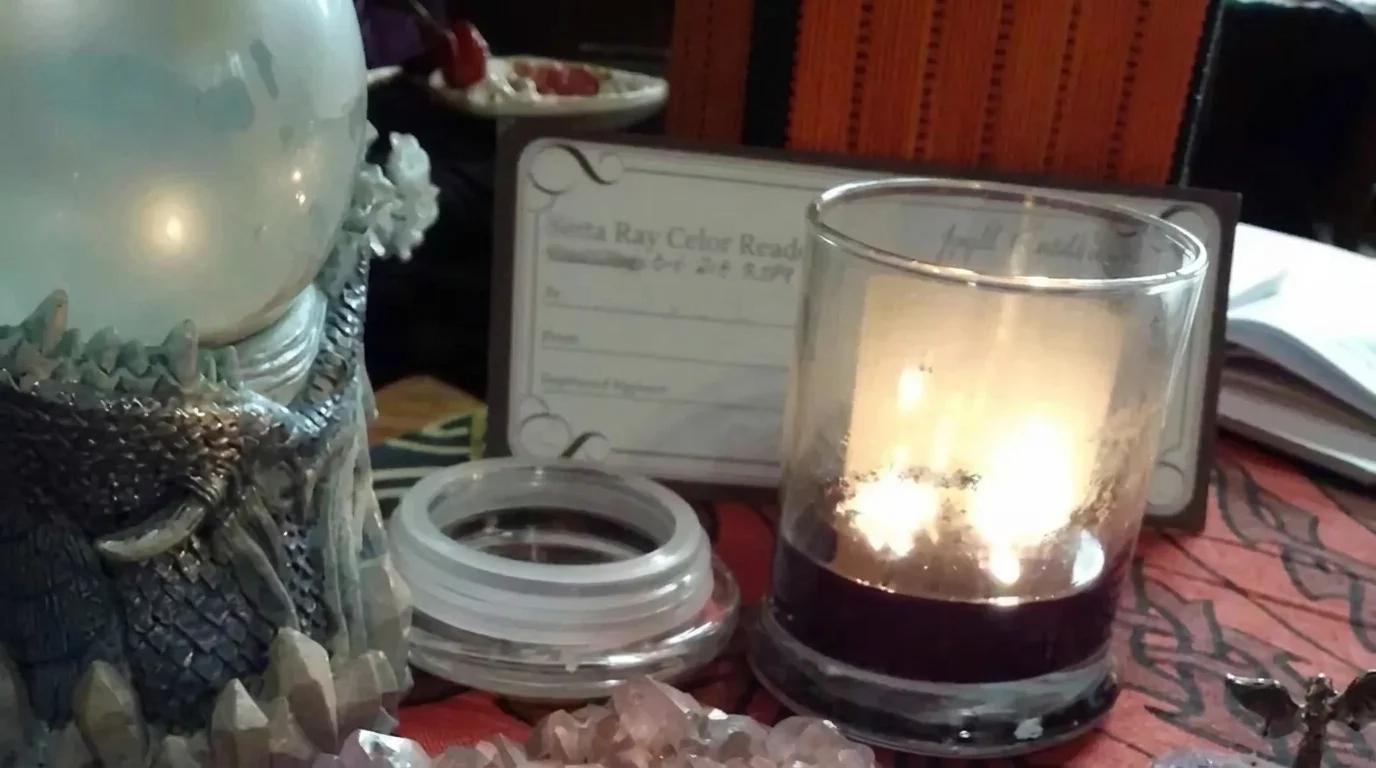 Glass crystal ball and glowing candle arranged on Berta's reading table