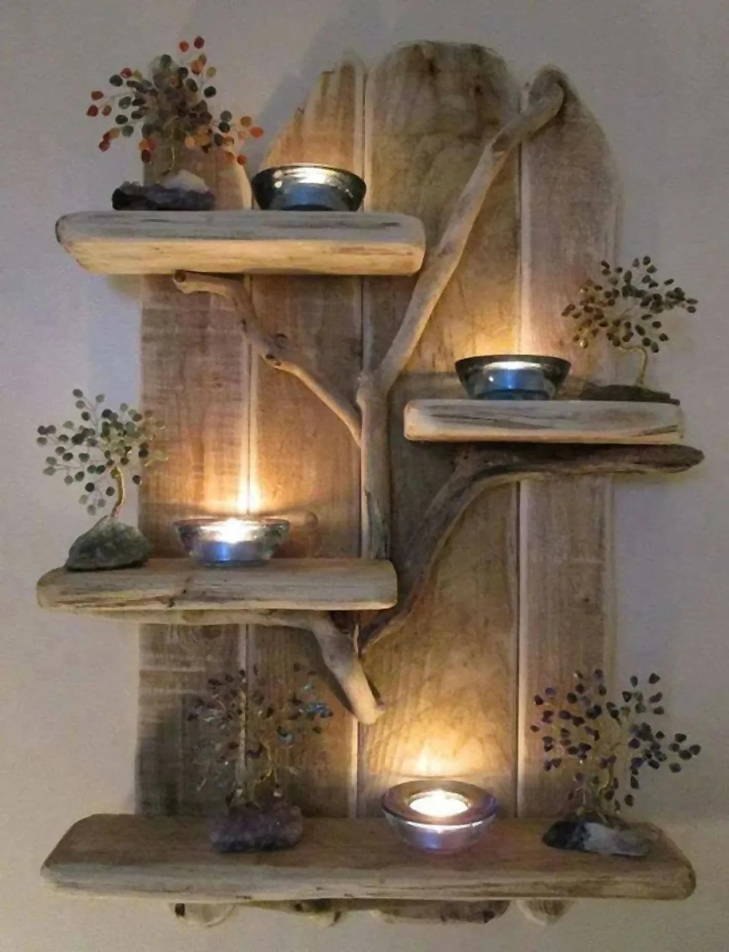 Driftwood wall shelf holding glowing tealight candles and gemstone trees