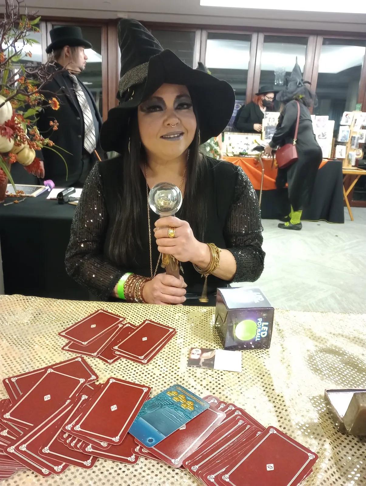 Card reader holding a crystal ball above a tarot spread at a community event