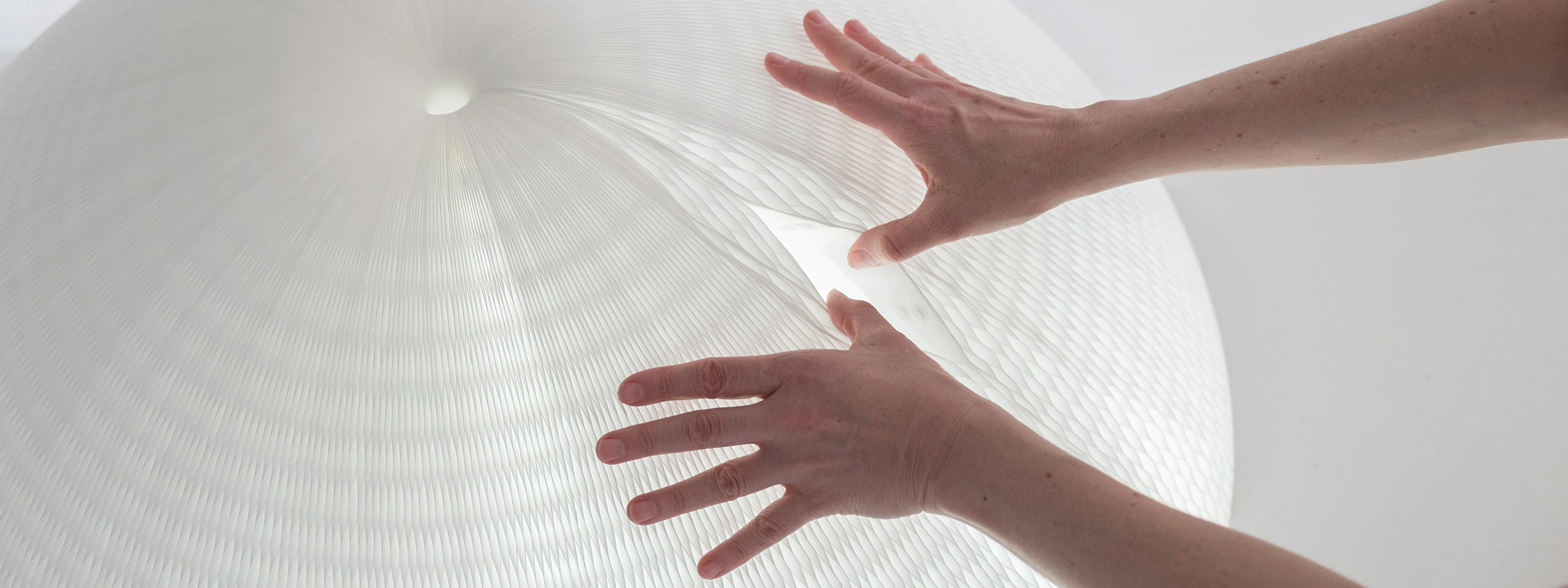 A pair of hands reveal the hidden magnet closure system for urchin softlight.