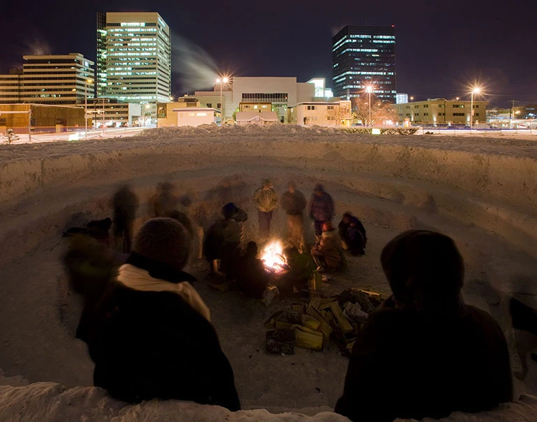 Alaskans gather around the fire at the northern sky circle installation.