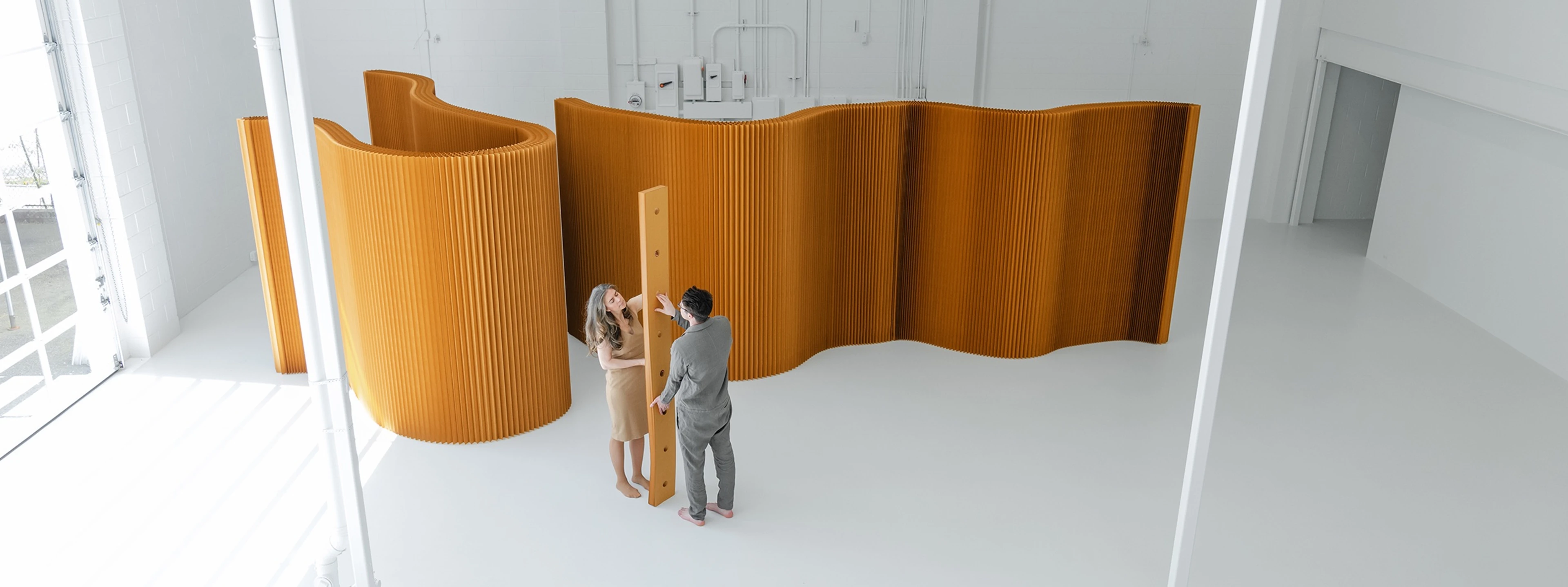 molo softwall modular paper partition in honeycomb brown creating a flexible room divider with people interacting in a bright studio.