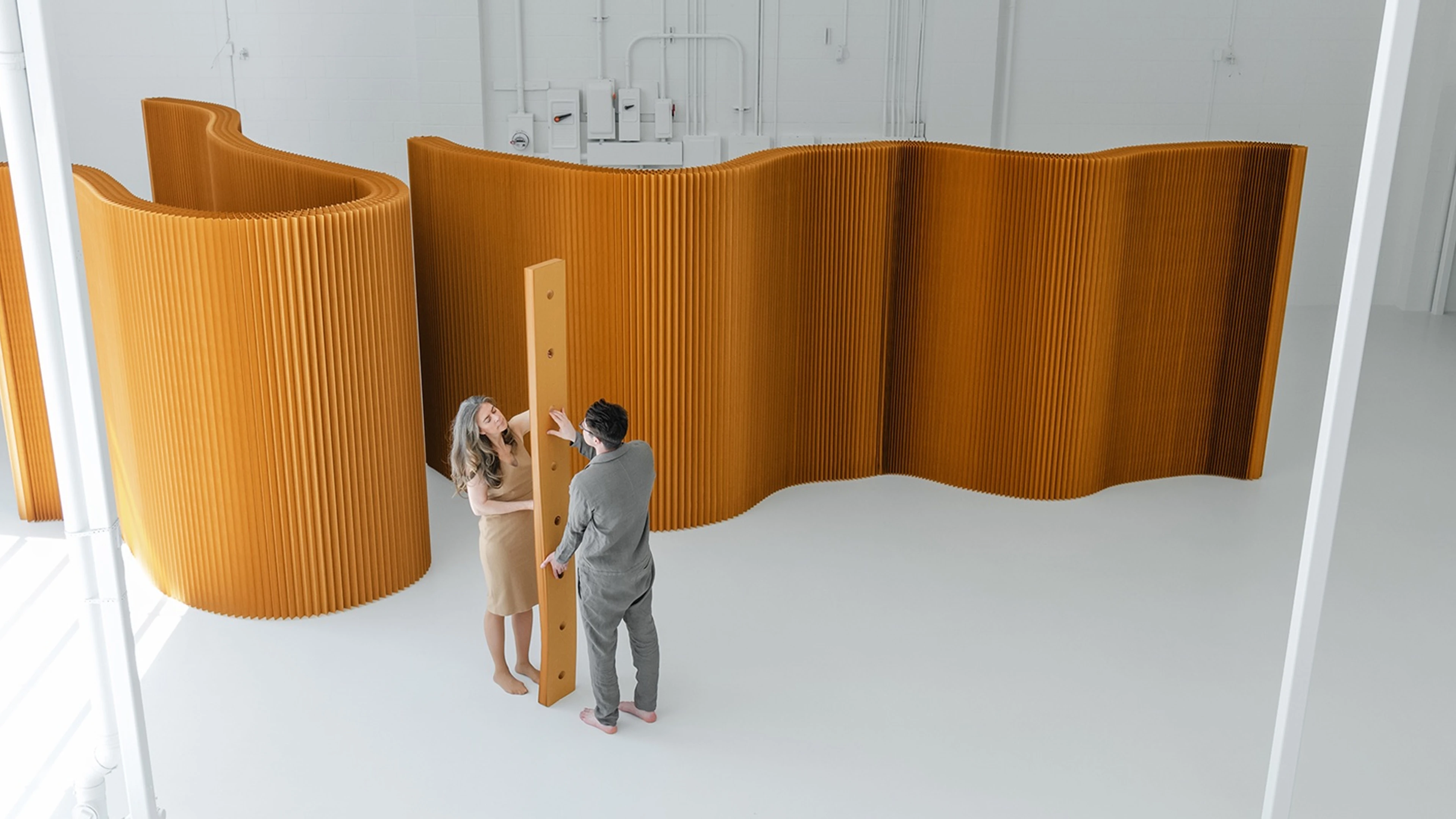 molo softwall modular paper partition in honeycomb brown creating a flexible room divider with people interacting in a bright studio.