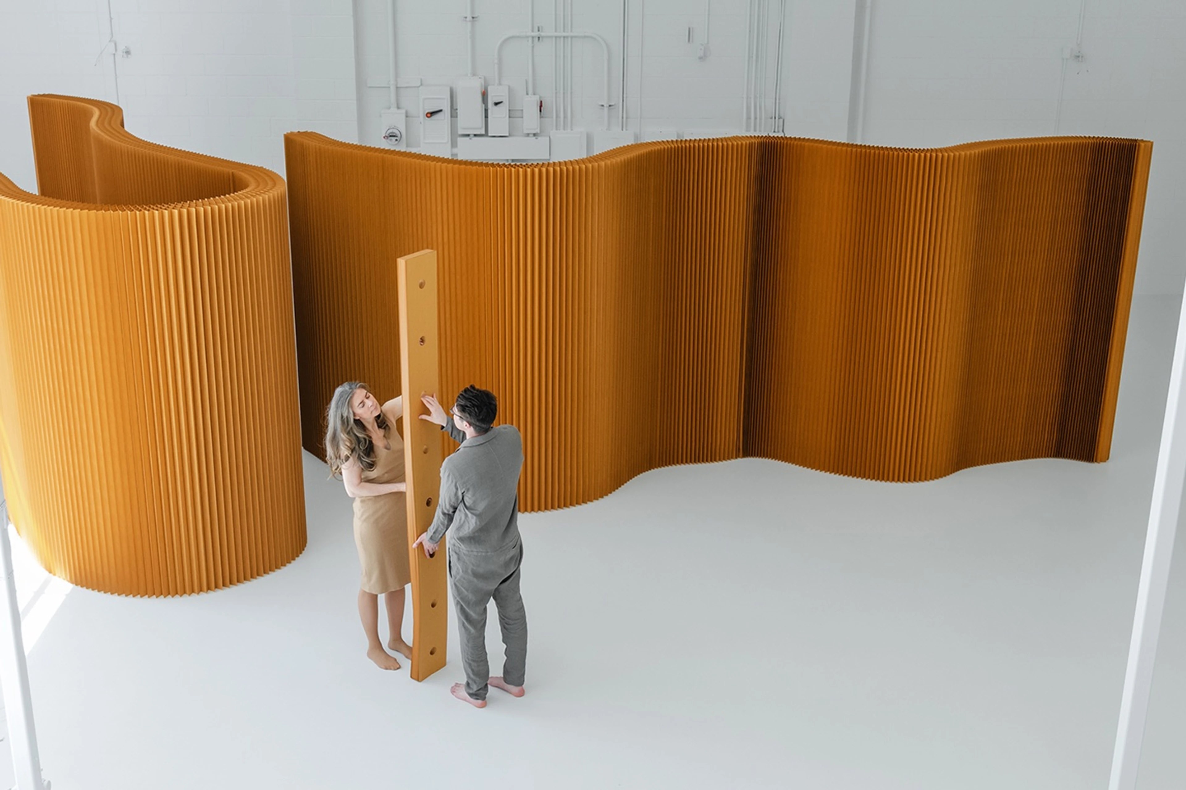 molo softwall modular paper partition in honeycomb brown creating a flexible room divider with people interacting in a bright studio.