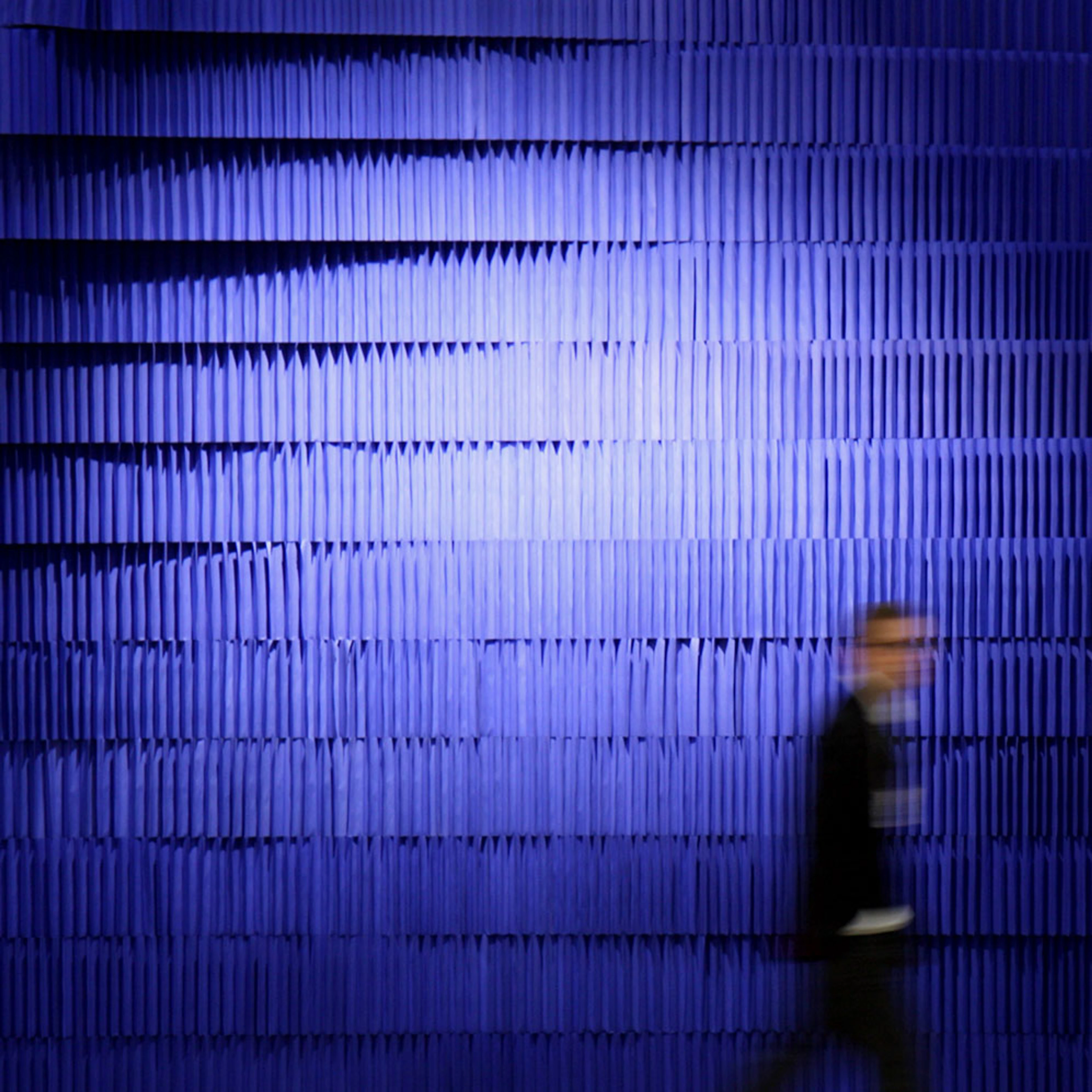 A ghostly figure passes by a wall made from stacked indigo softblock - acoustic design