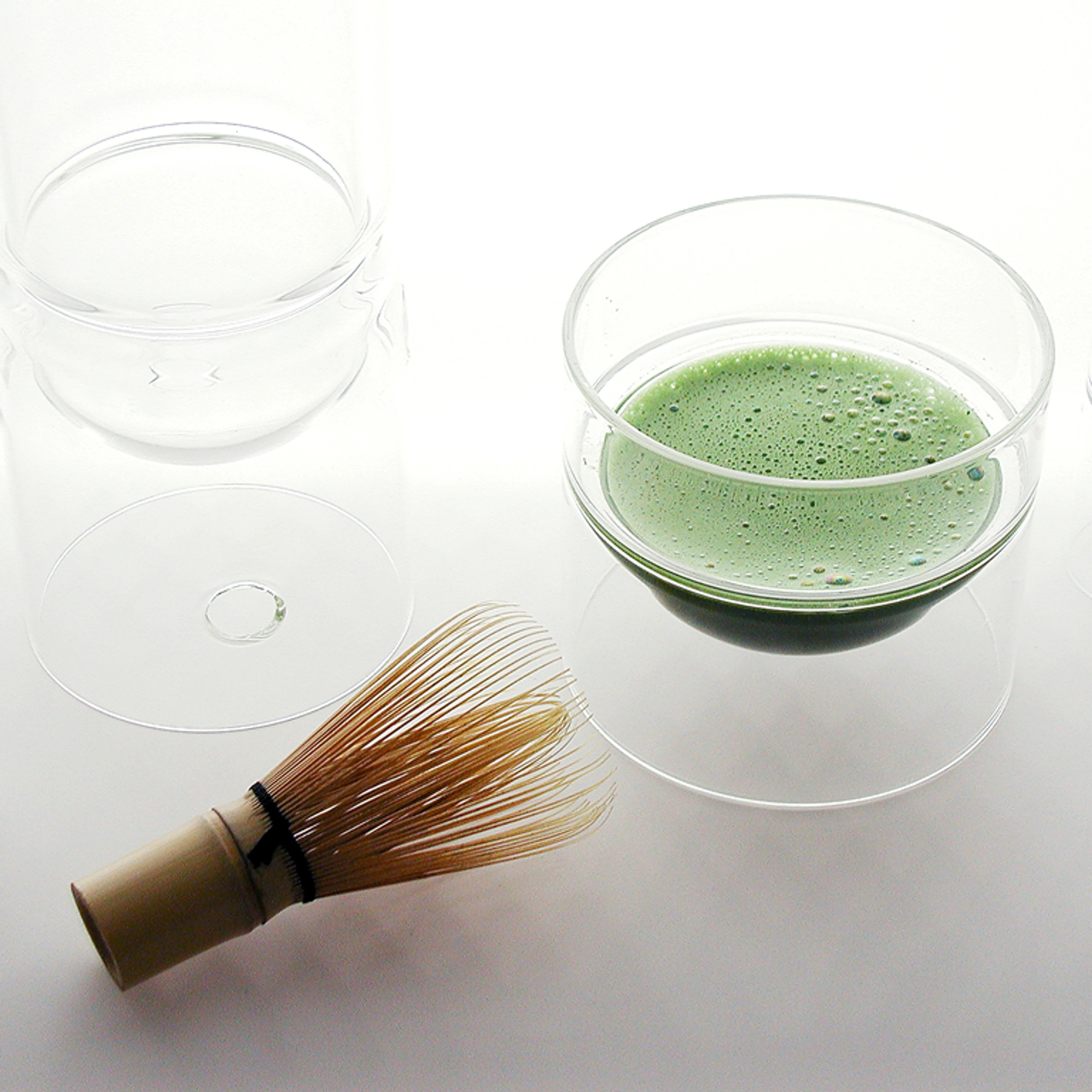 matcha green tea in a glass cup with a whisk.