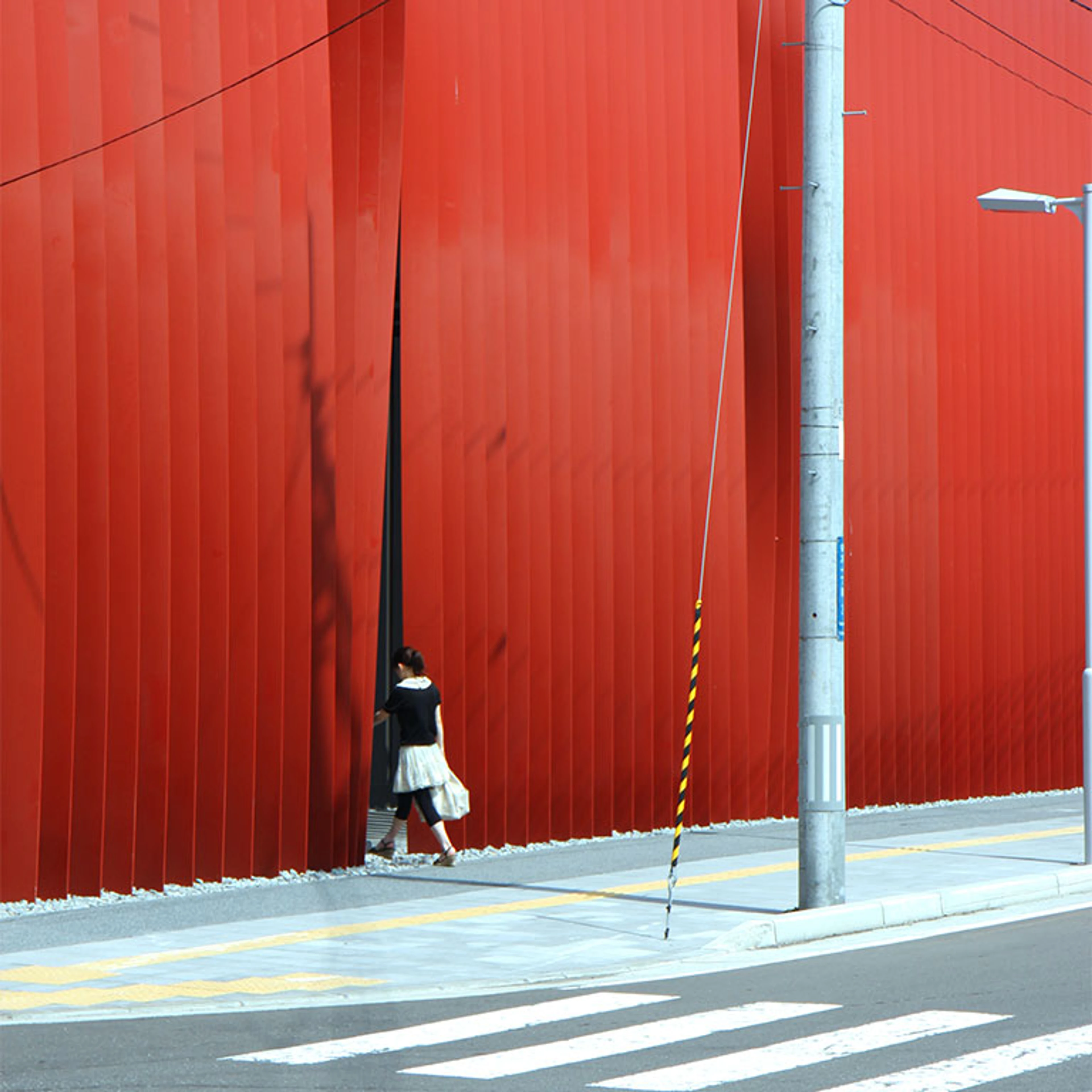 a woman disappears behind the veil of steel ribbons hanging from Aomori Nebuta House.
