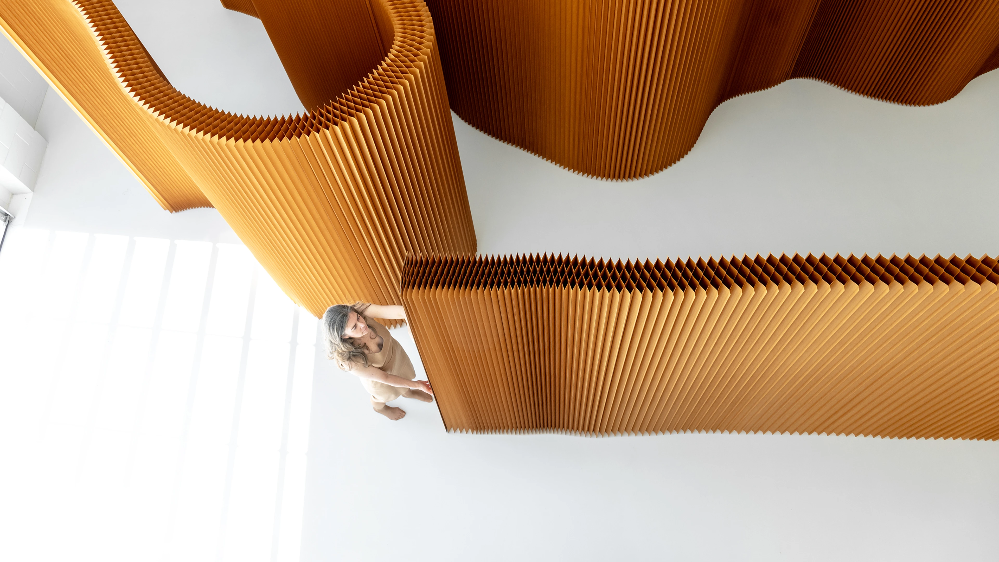 Overhead view of a woman stretching open a paper softwall.