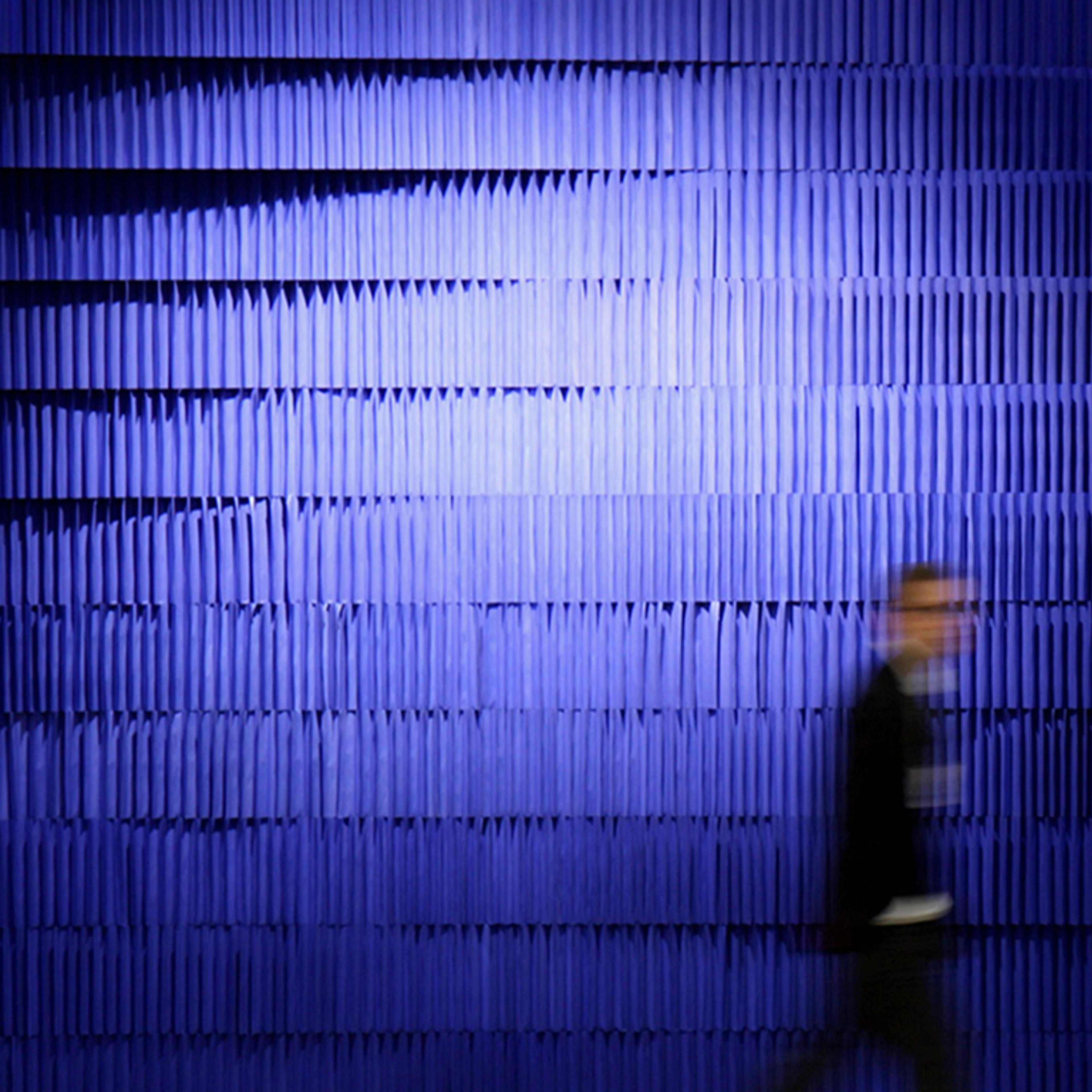 silhouette passing by a wall made from flexible paper building blocks - acoustic design