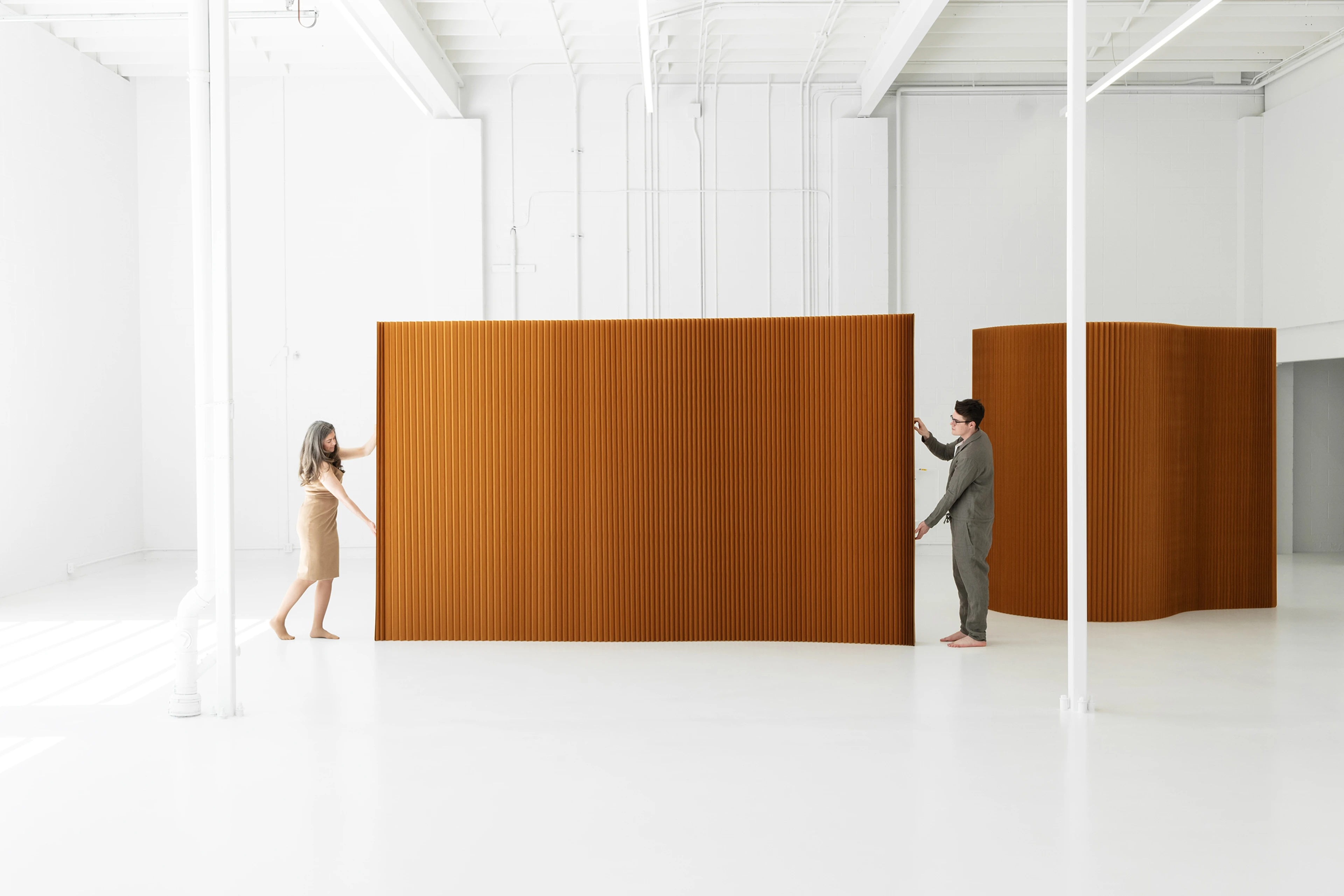 two people opening flexible wall partition brown paper