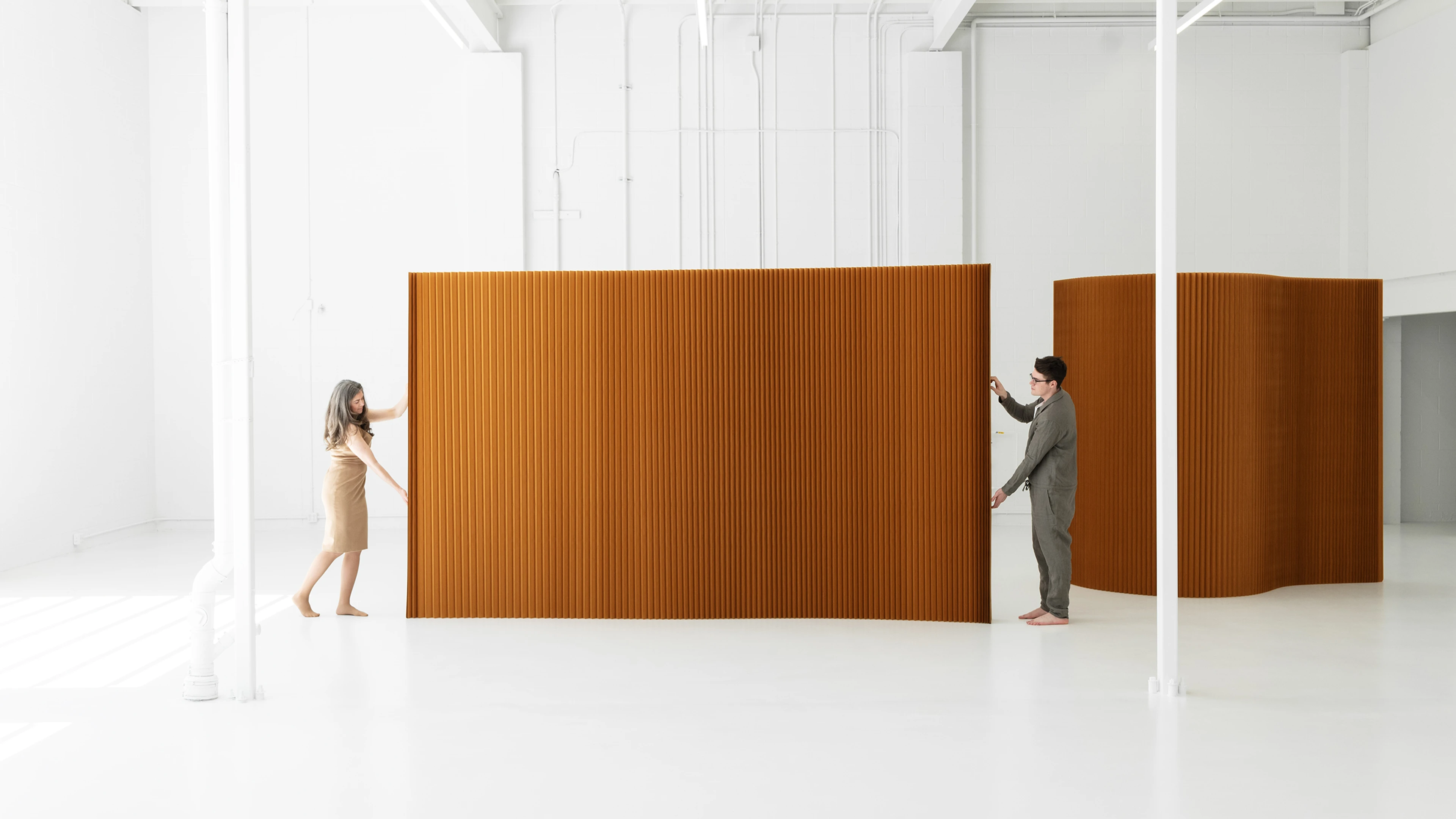 two people opening flexible wall partition brown paper
