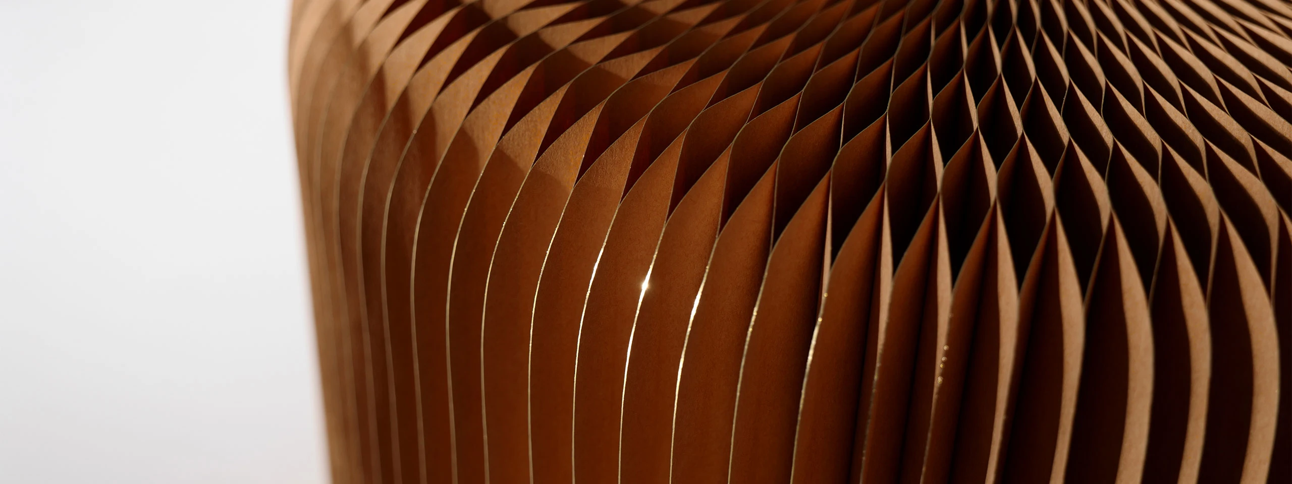 light reflects off the gilded paper pleats of a softseating fanning stool