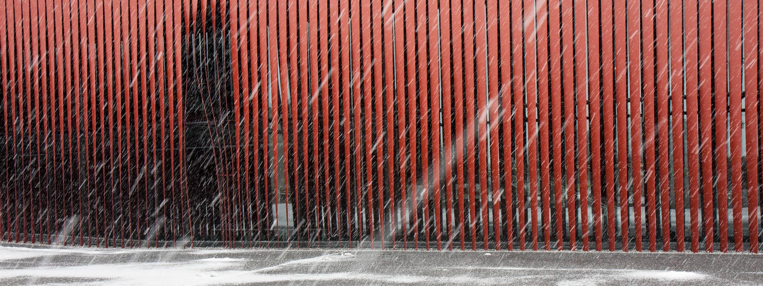 snowfall against the red facade of Nebuta House Warasse in Aomori.