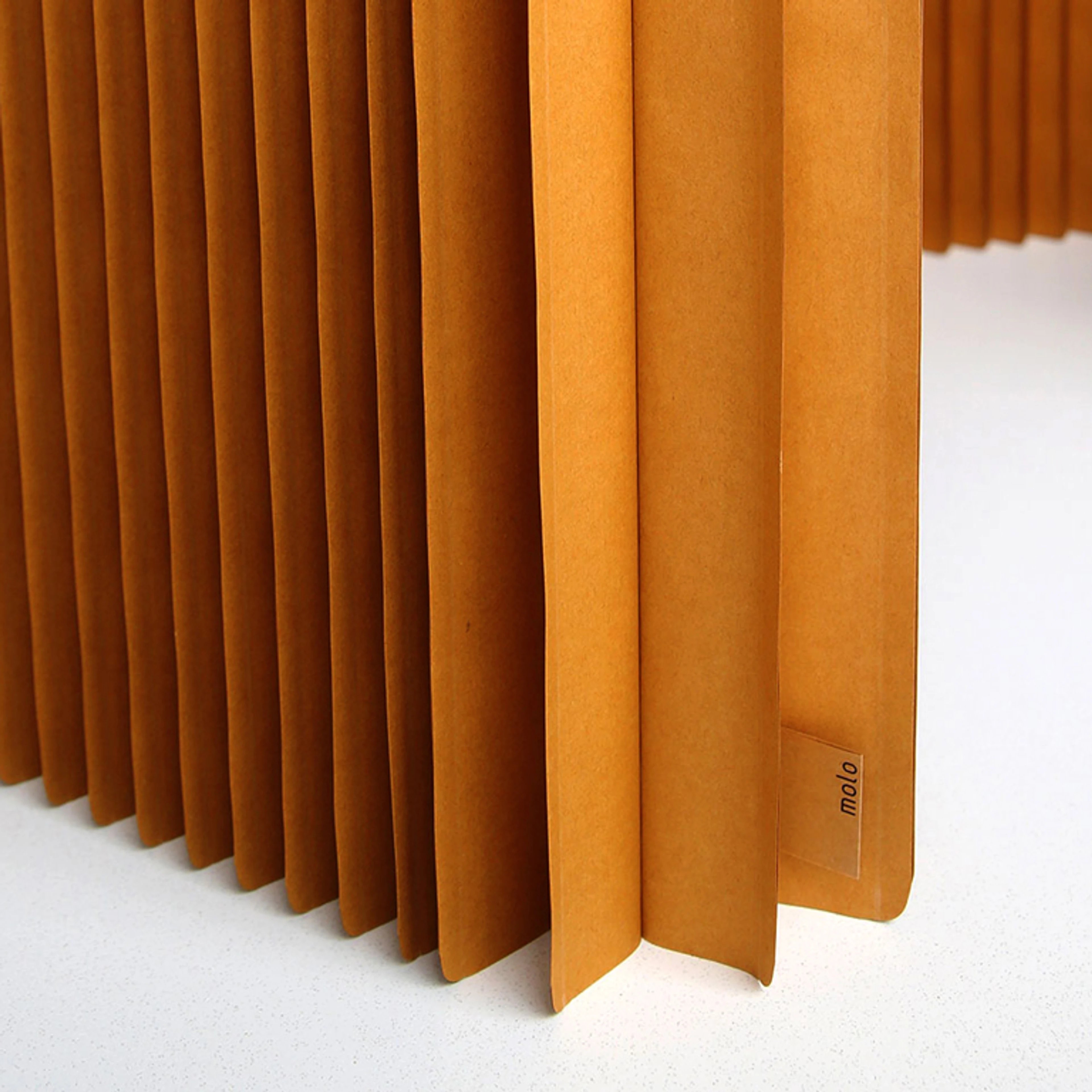 Paper is often thought of as fragile and disposable in our culture. When we began our studies and experiments of folding and laminating paper we paid close attention to the direction of the grain and learned about the strength of using long, slender, flexible fibre from northern trees (which grow slower). We discovered that paper could be a viable structural material and realized that we hade never seen it used architecturally in a way that celebrated both its strength and resiliant flexibility. Laminating our heavyweight kraft paper into vertical cellular structures achieves surprising and impressive strength. The flexibility of these products allows them to adapt and move with the changes in your life. Small design details also contribute to longevity, such as the radius cut where the corners of softwall meet the floor, reducing friction and avoiding signs wear and tear (dog ears) from movement. We thoughtfully select materials, colours and finishes that either have a very strong lightfastness or age gracefully with attractive patina over time.