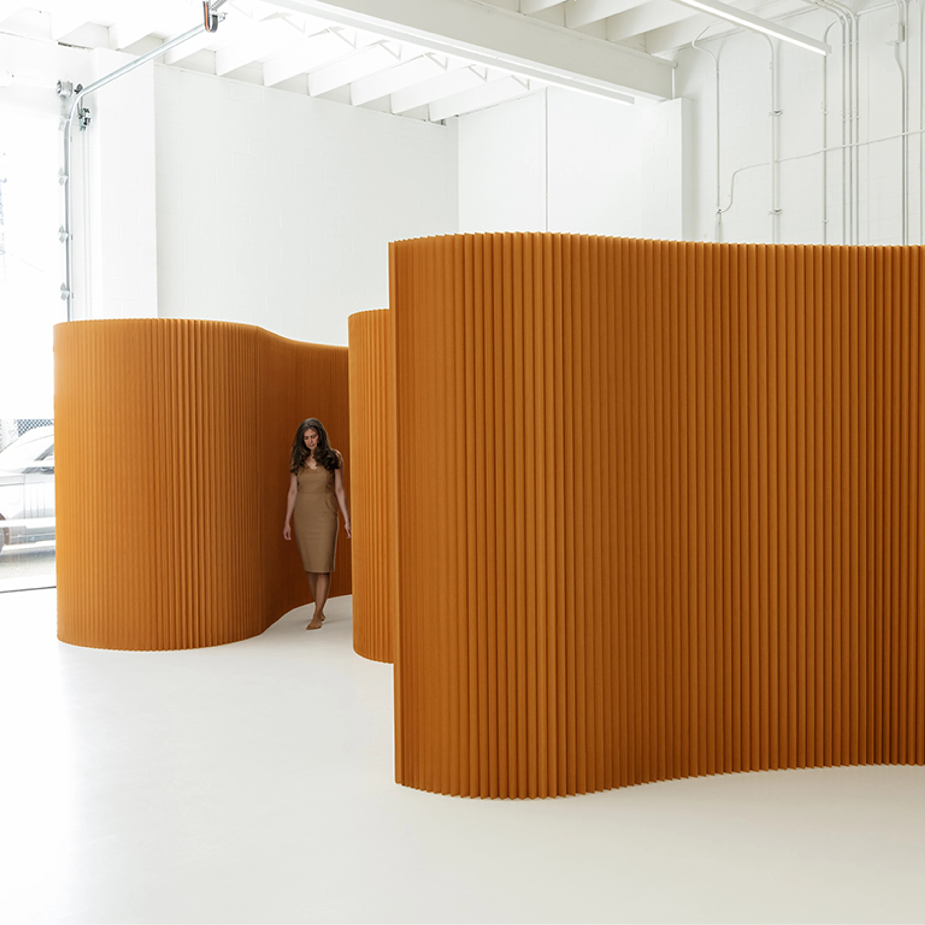 woman walking near brown paper softwall flexible wall partition