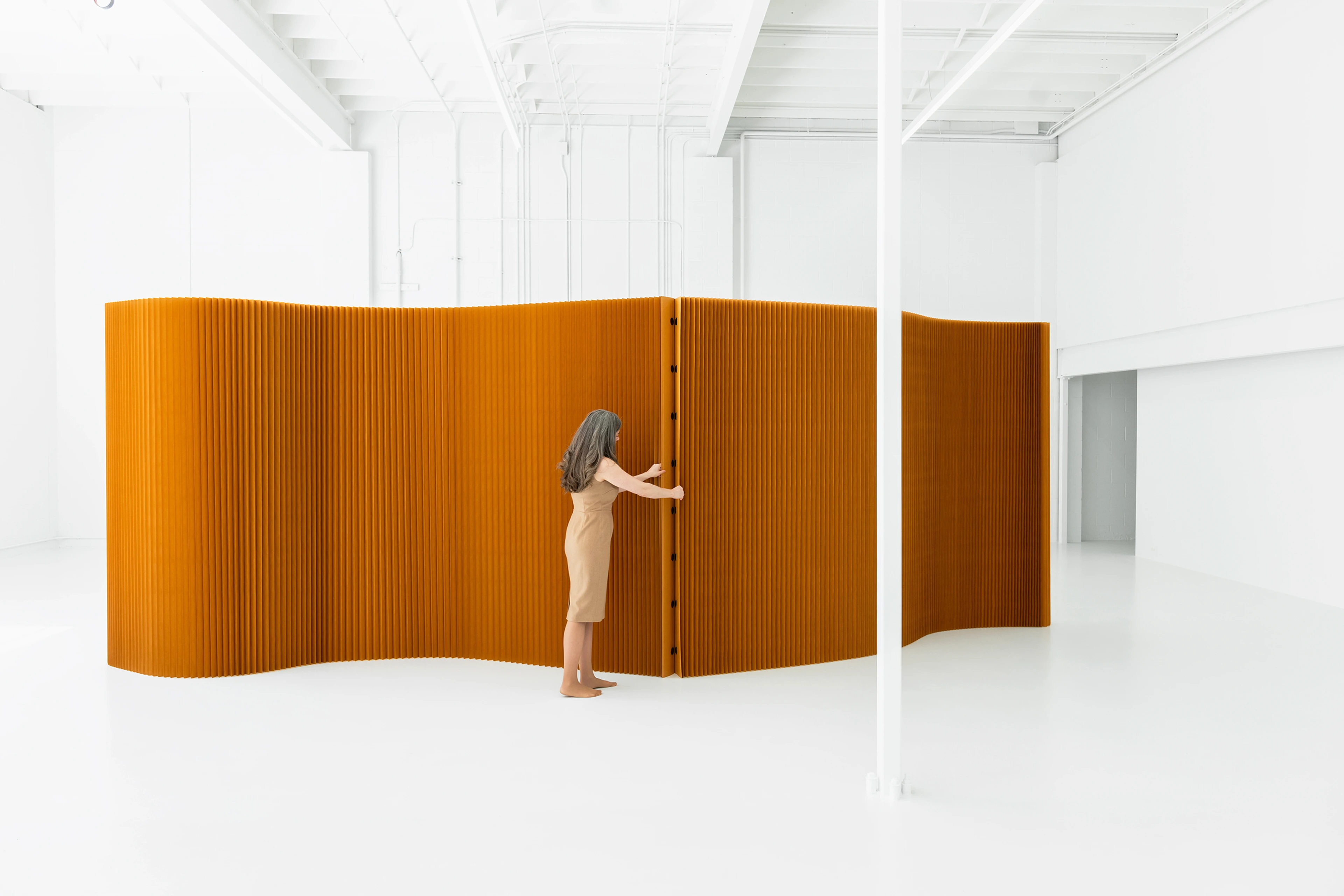 A woman connects two paper softwalls by their magnetic end panels.