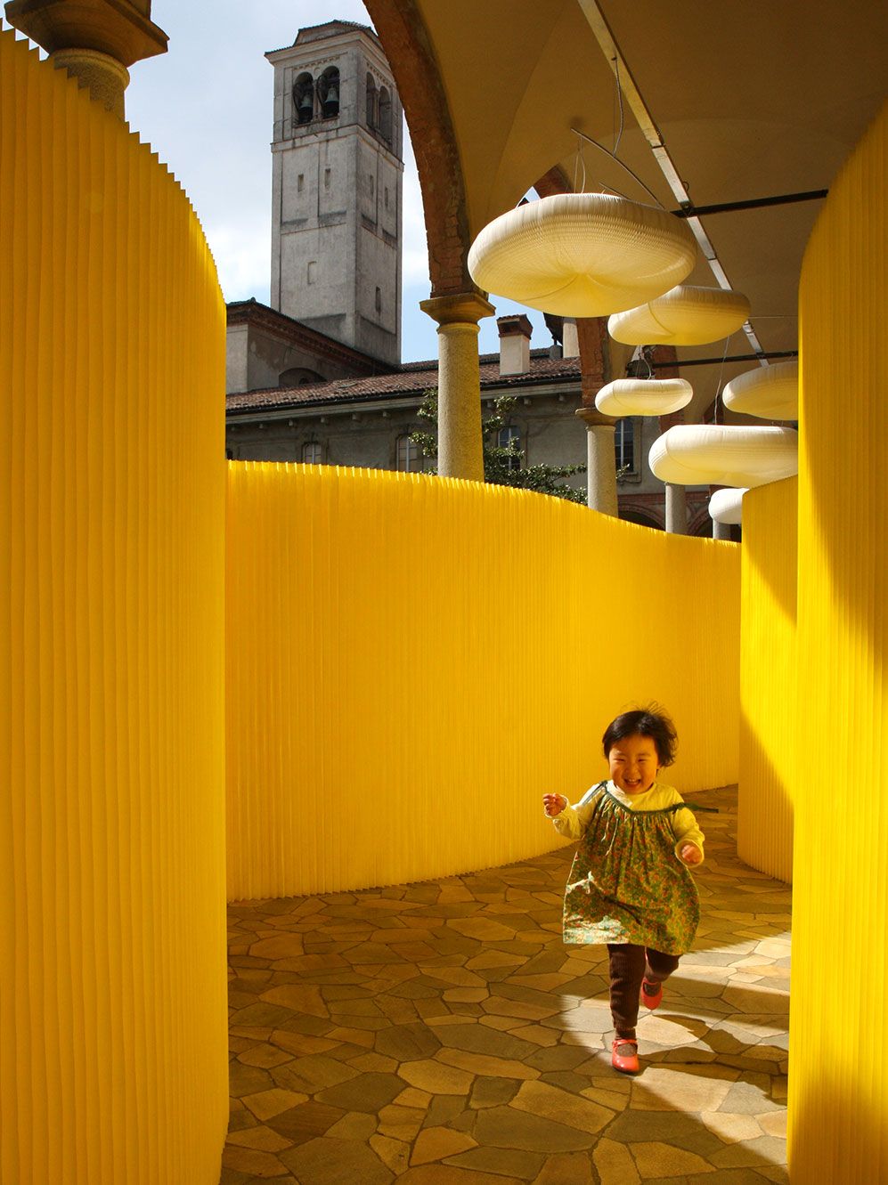 A child plays in a corridor of yellow textile softwalls at MOST in Milan.