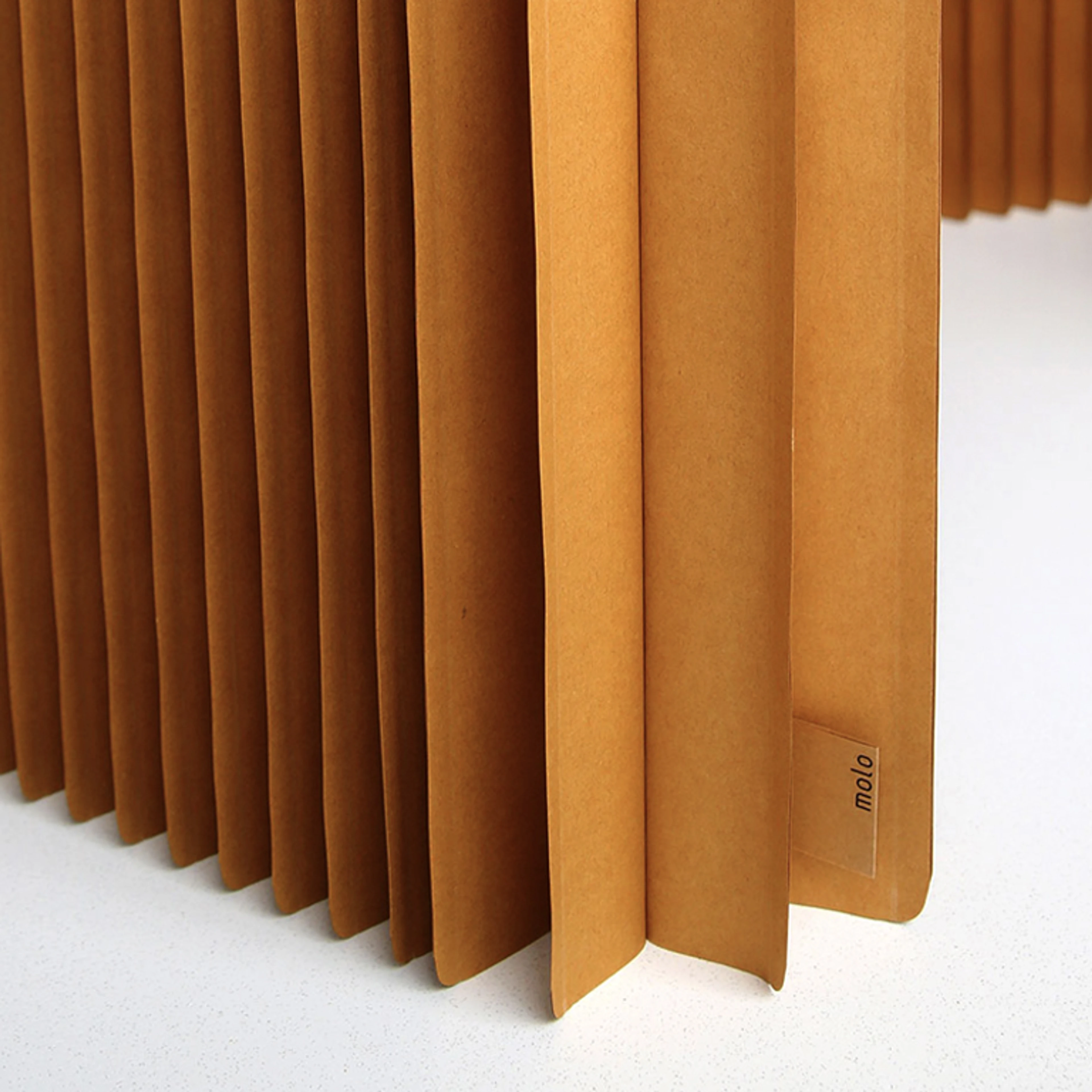 A paper folding wall that is being pulled open from its flat pack form. softwall is a freestanding acoustic partition that can expand into any shape.