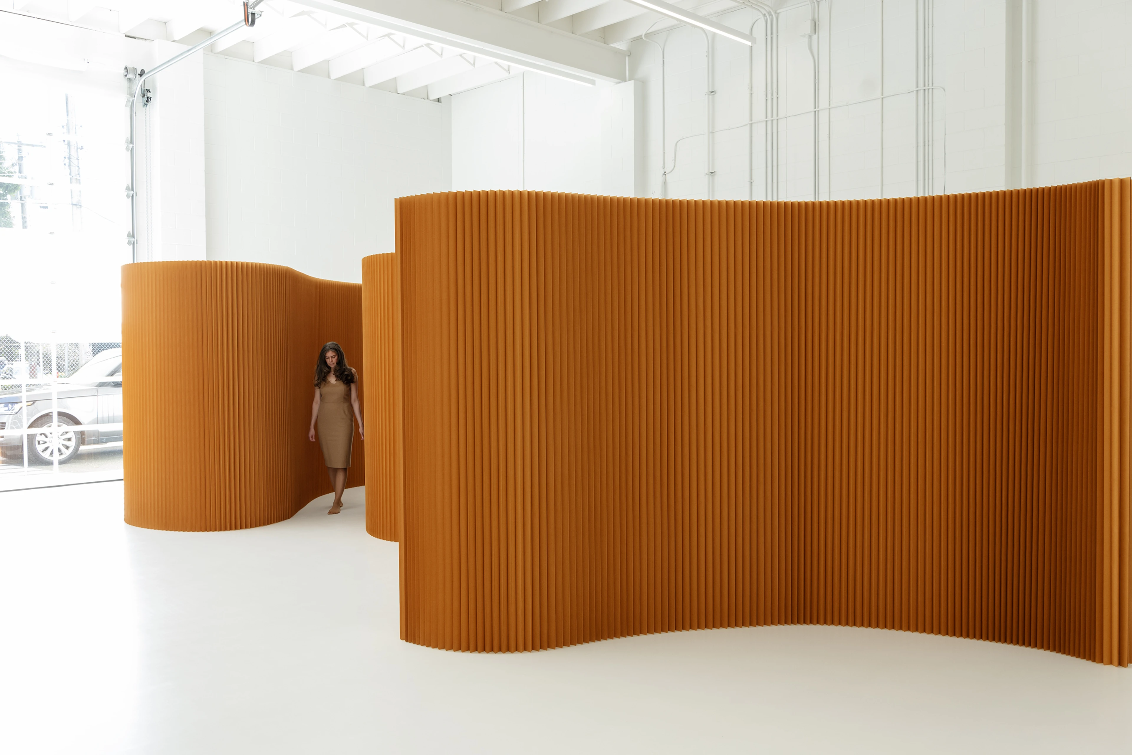A woman wanders through a space delineated by paper softwalls.