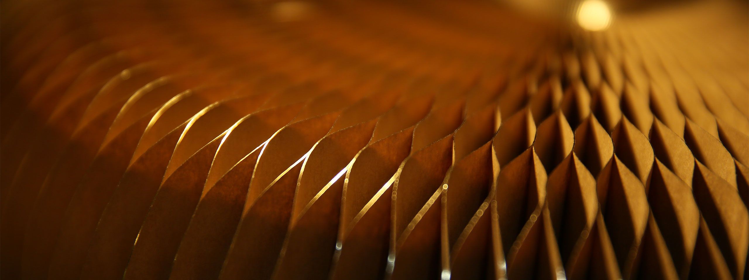 detail of light glittering on the gilded paper pleats of a softseating fanning stool