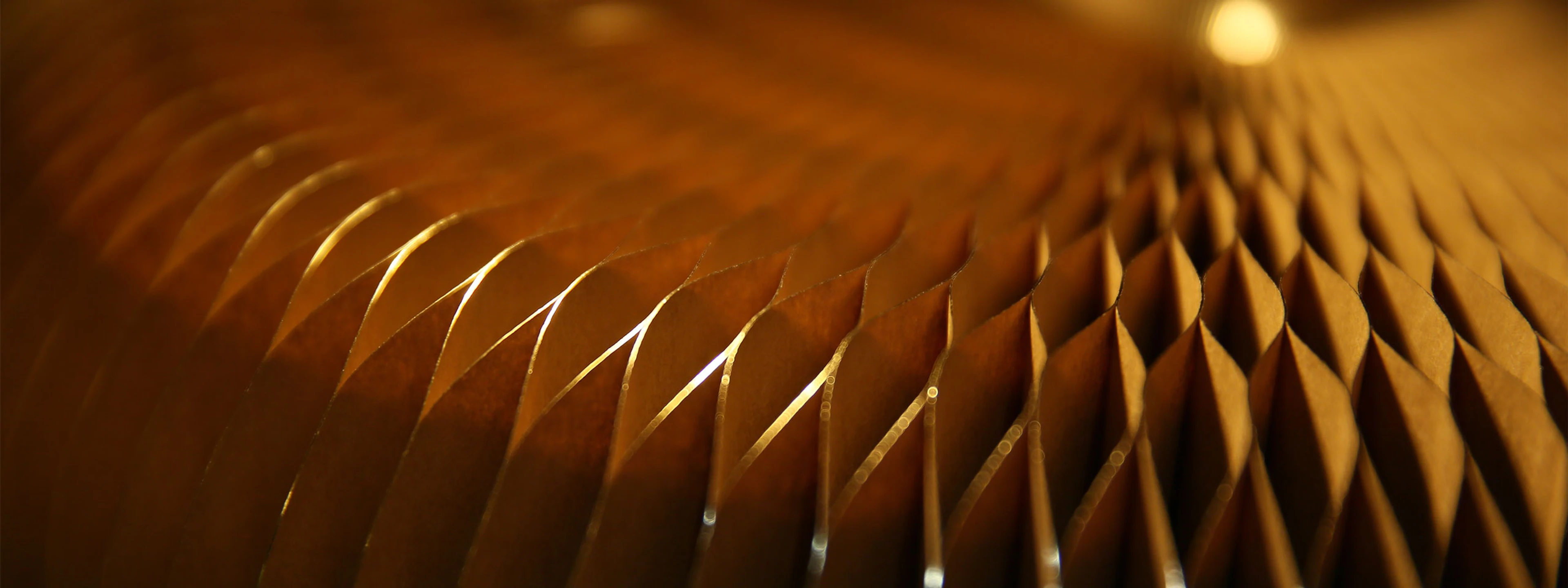 detail of light glittering on the gilded paper pleats of a softseating fanning stool