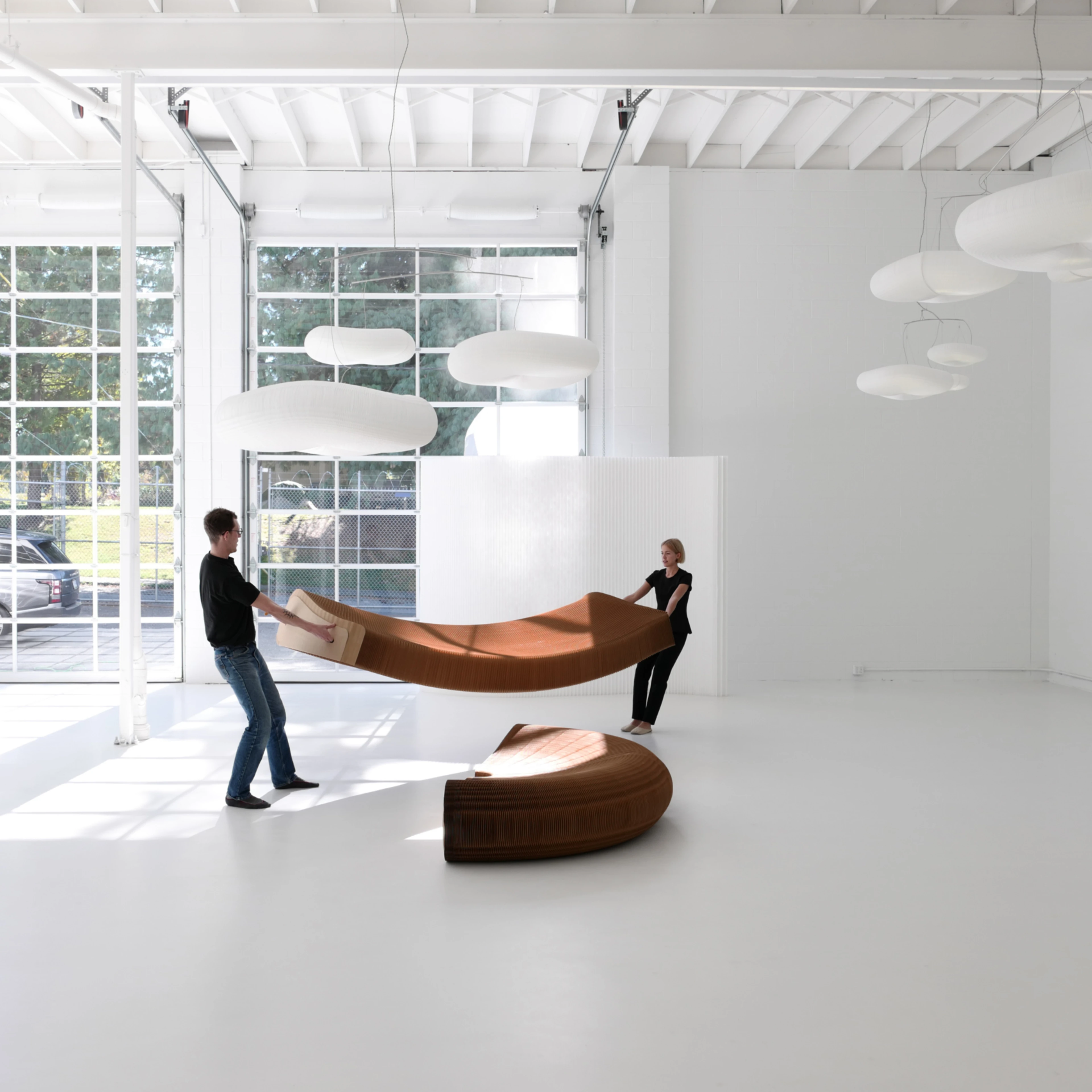 two people stretch open a third of the base for softseating lounger