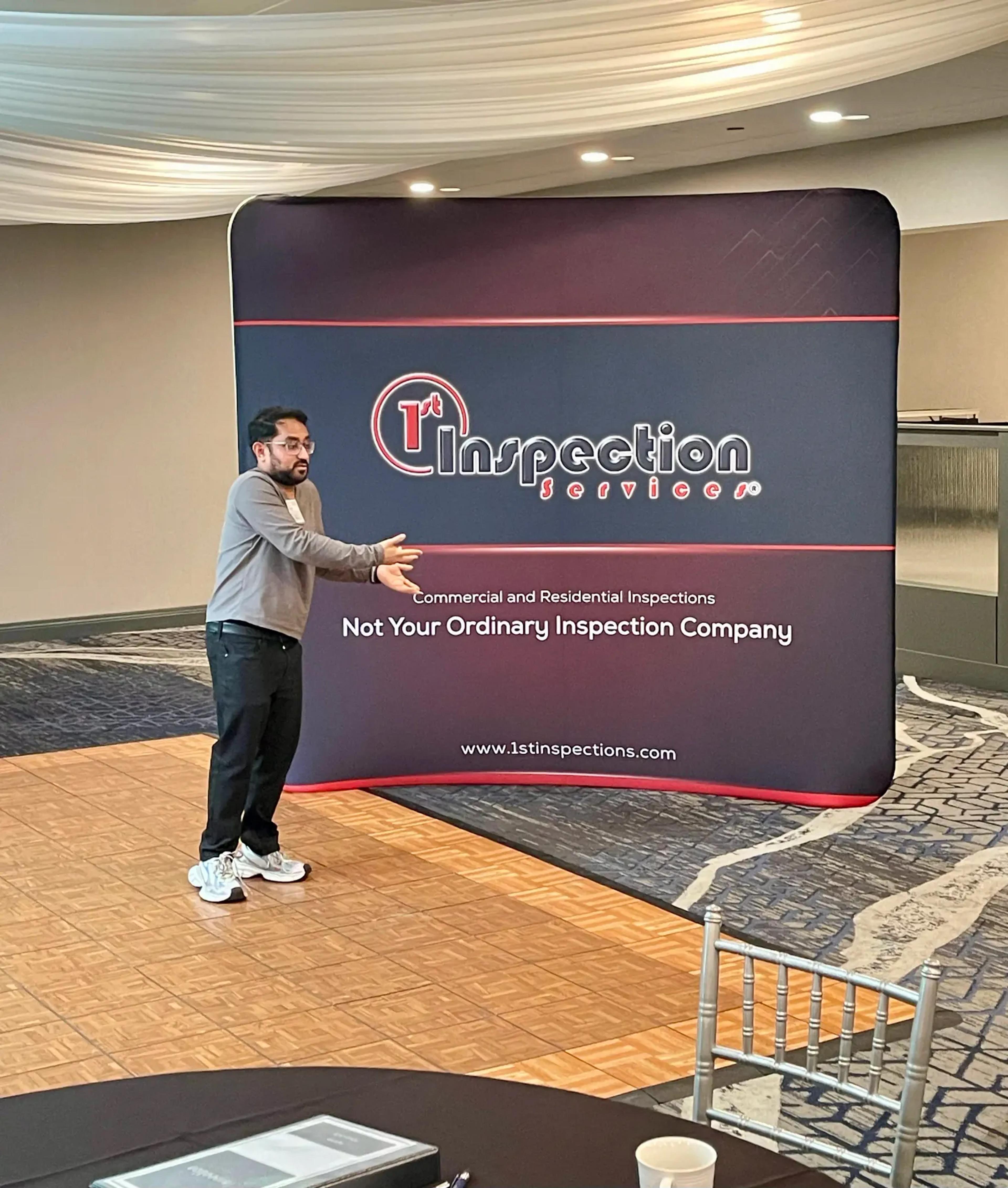 Presenter in front of the 1st Inspection Services "Not Your Ordinary Inspection Company" banner