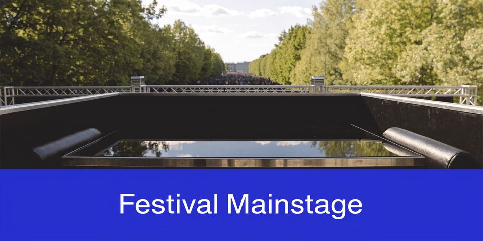 A view from a festival mainstage overlooking a large crowd between rows of tall green trees.