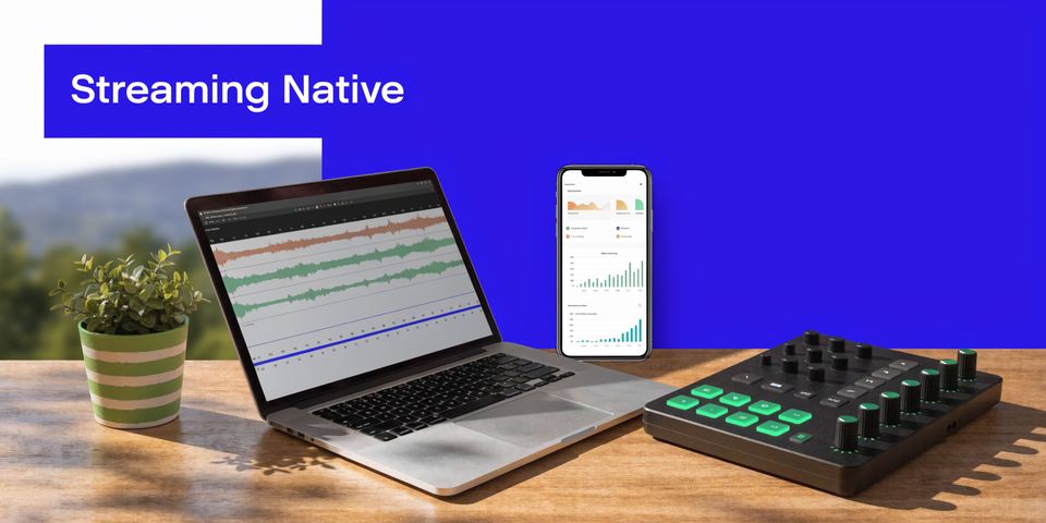 A modern workspace featuring a laptop showing waveforms, a smartphone with analytics, and a professional audio controller.