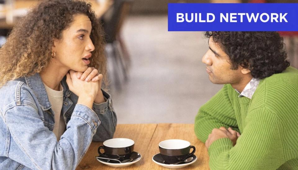 A woman and a man sitting at a cafe table having a professional conversation about networking together.
