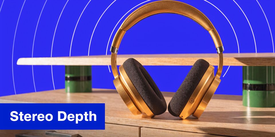 A pair of premium gold-colored headphones resting on a wooden surface with a blue background.