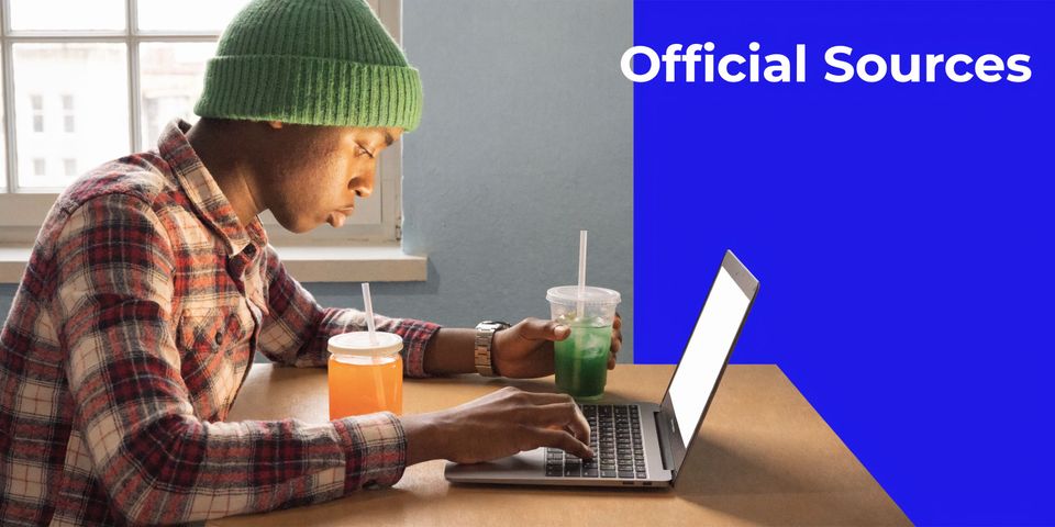 A young person wearing a green beanie working on a laptop while drinking colorful beverages at a desk.