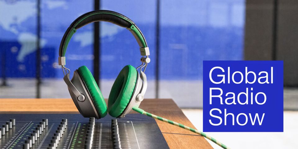 A professional audio mixing console and vibrant green studio headphones sitting on a wooden desk.