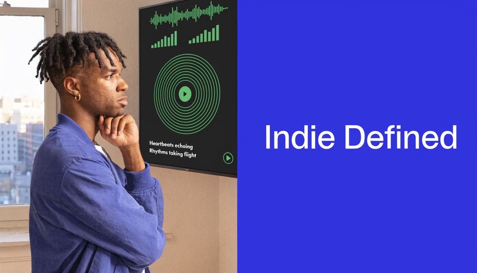 A young man looking thoughtfully at a screen displaying a digital music player interface with green waveforms.