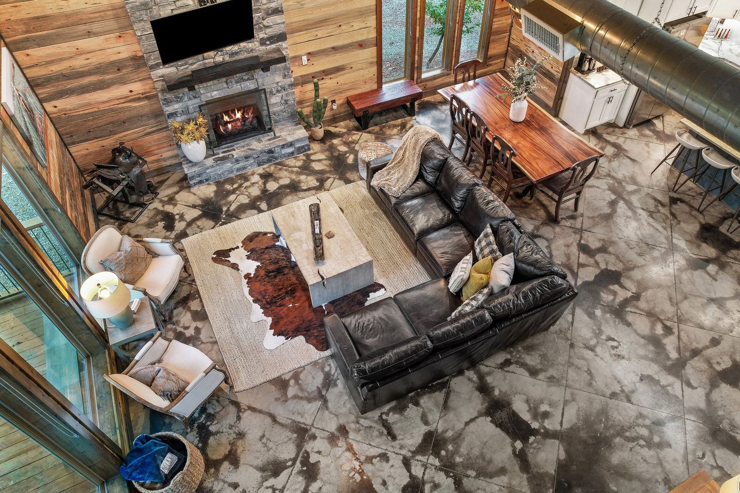 The cabin living room from above, sofas gathered around a stone fireplace