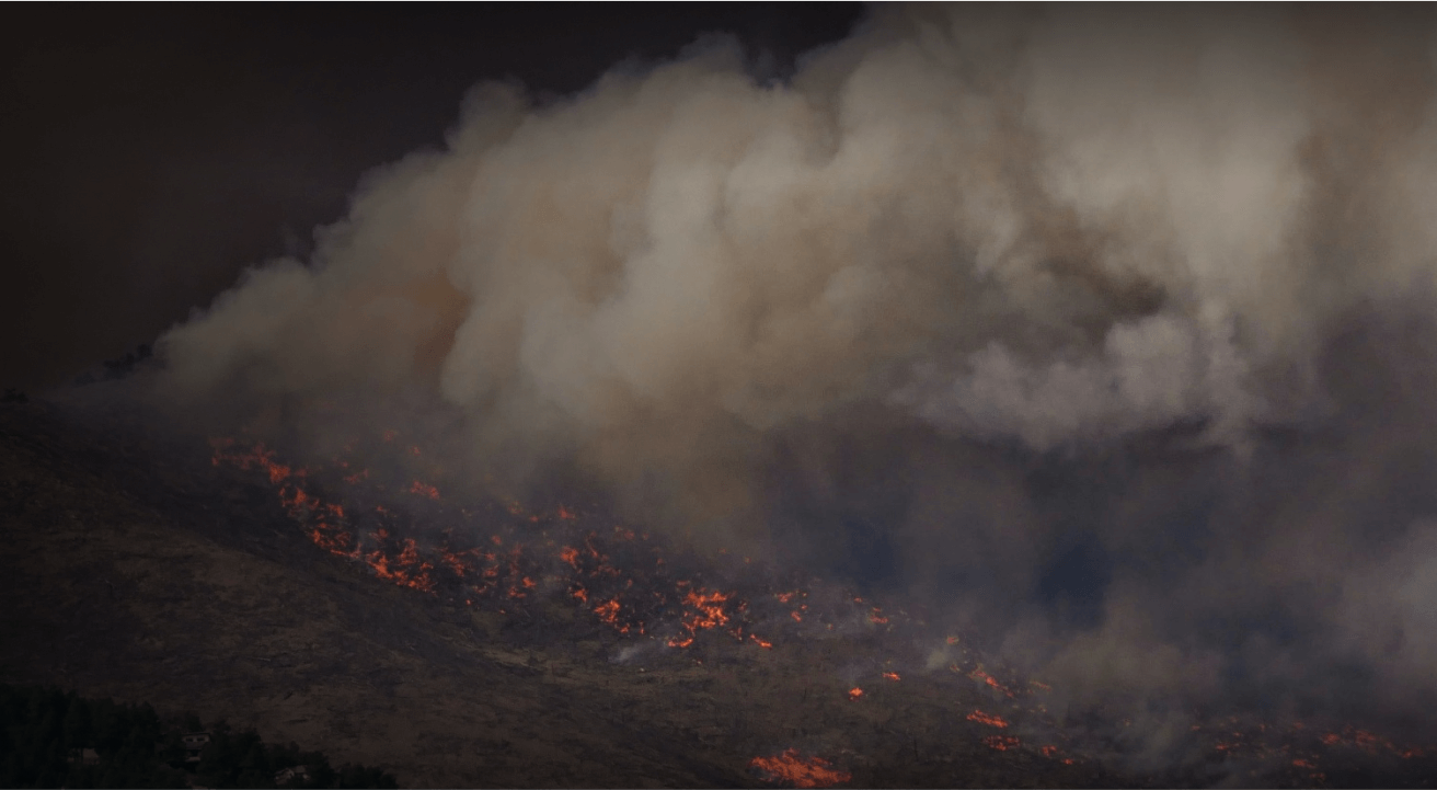 A wildfire spreading across a forest mountain range