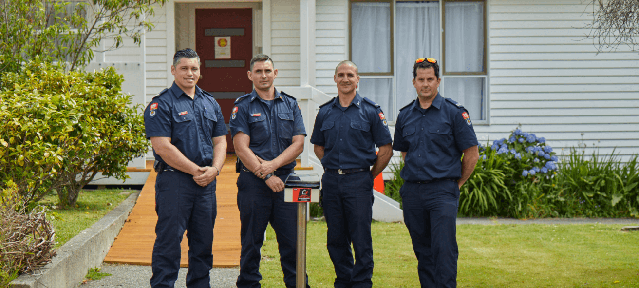 A group of four firefighters standing outside a building