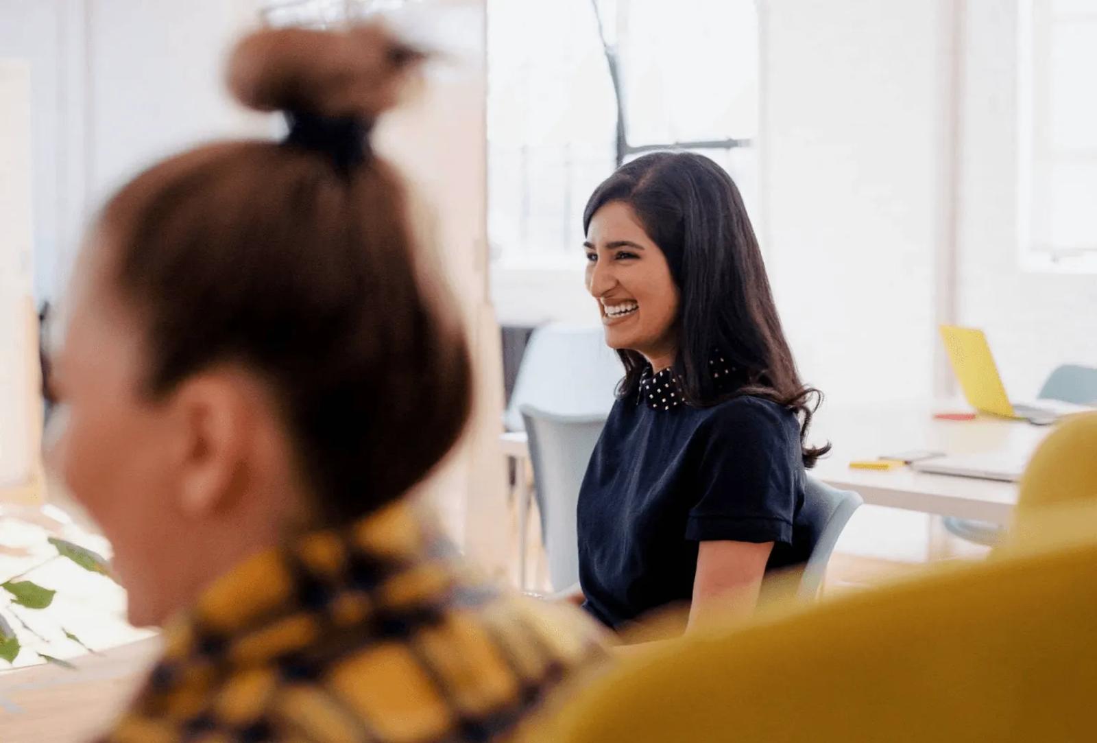 Two women laughing together in a bright office