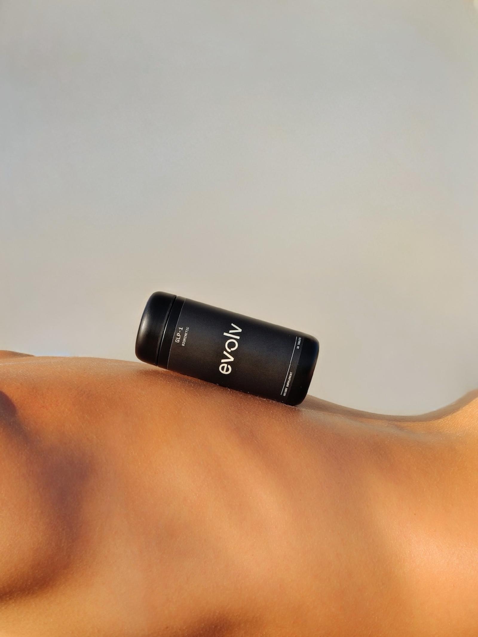 Black Evolv GLP-1 biomimetic supplement bottle resting on a person's bare hip