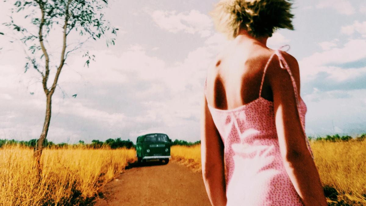 Cover details of The Dead Heart by Douglas Kennedy showing a woman in a pick dress looking at a green car