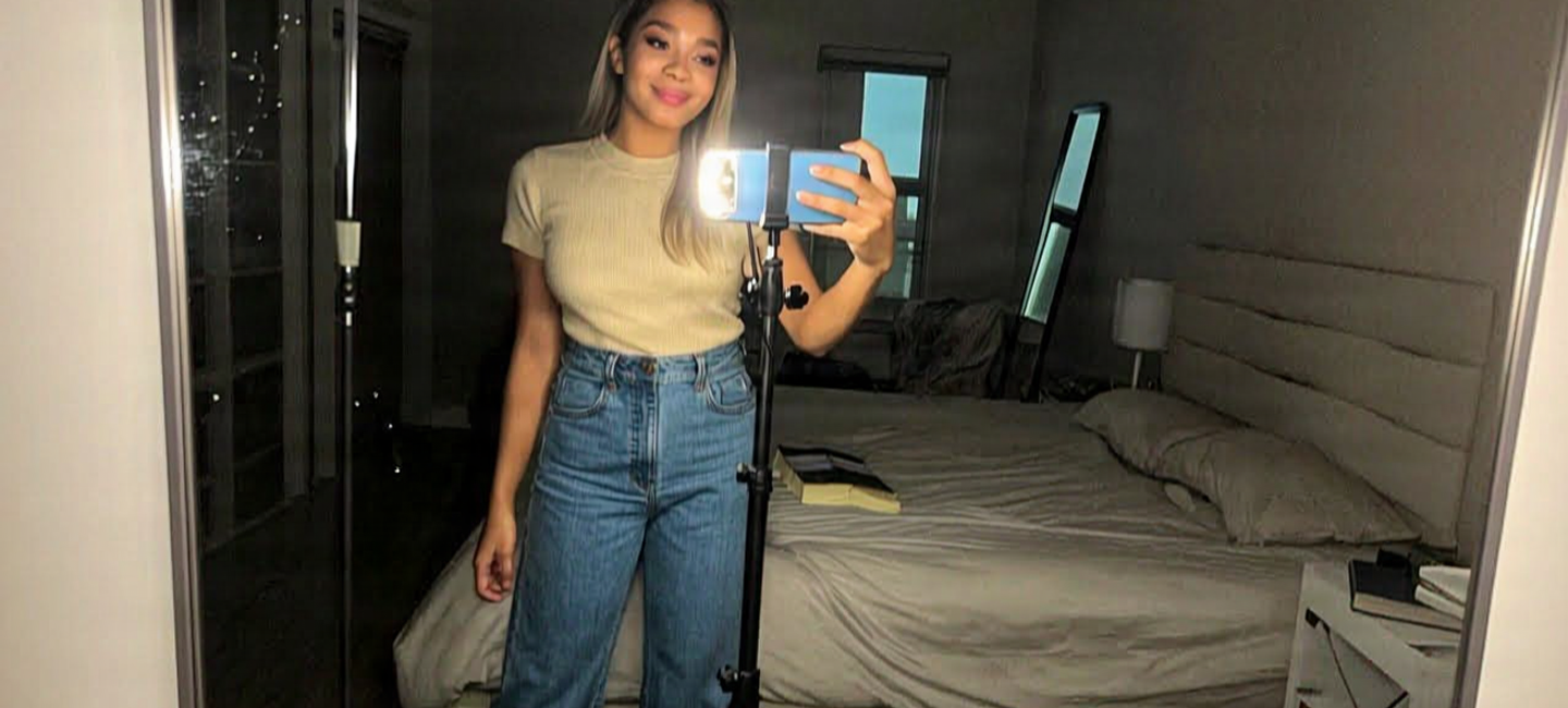 Woman recording a selfie video with a ring light in her bedroom
