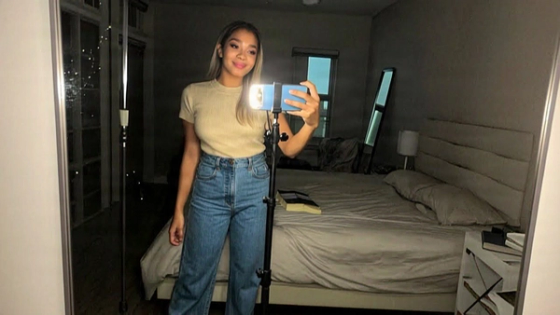 Woman recording a selfie video with a ring light in her bedroom