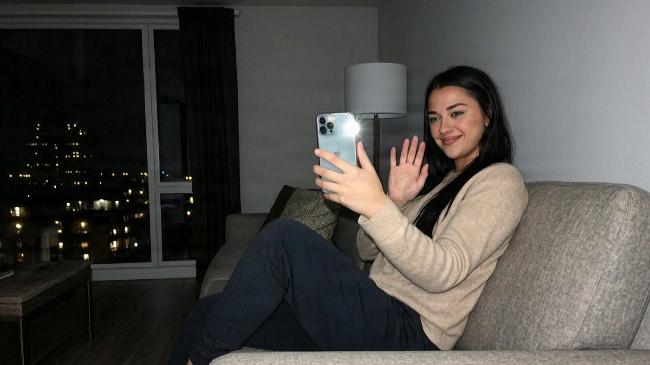 Woman on the sofa at night waving at her phone during a video call