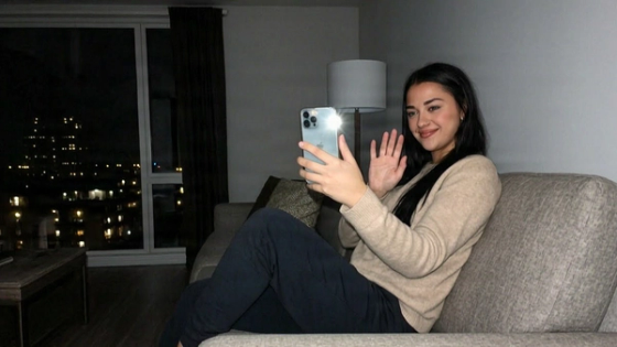 Woman on the sofa at night waving at her phone during a video call
