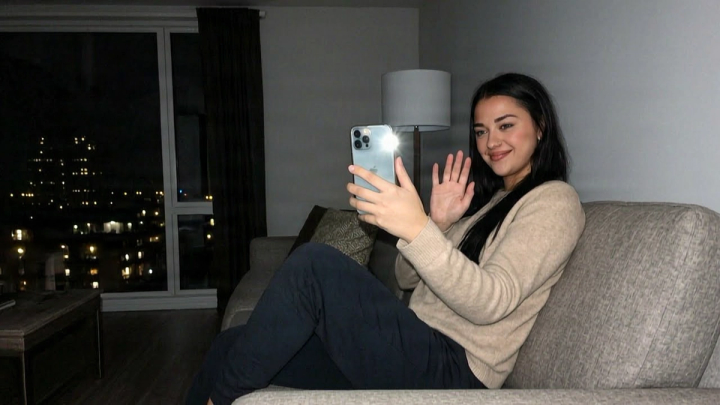 Woman on the sofa at night waving at her phone during a video call