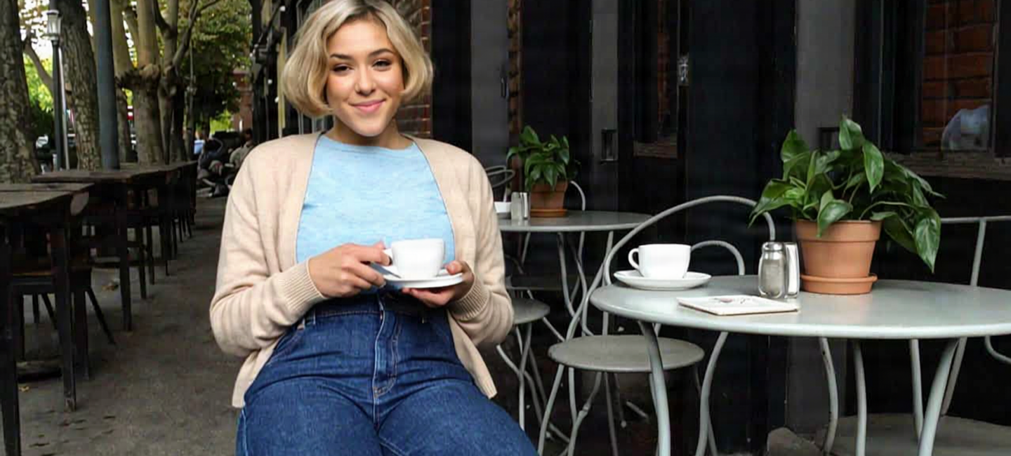 Smiling woman holding a coffee cup at an outdoor cafe