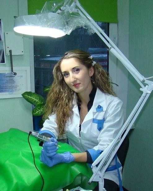 Мастер в белом халате с аппаратом для татуажа в кабинете