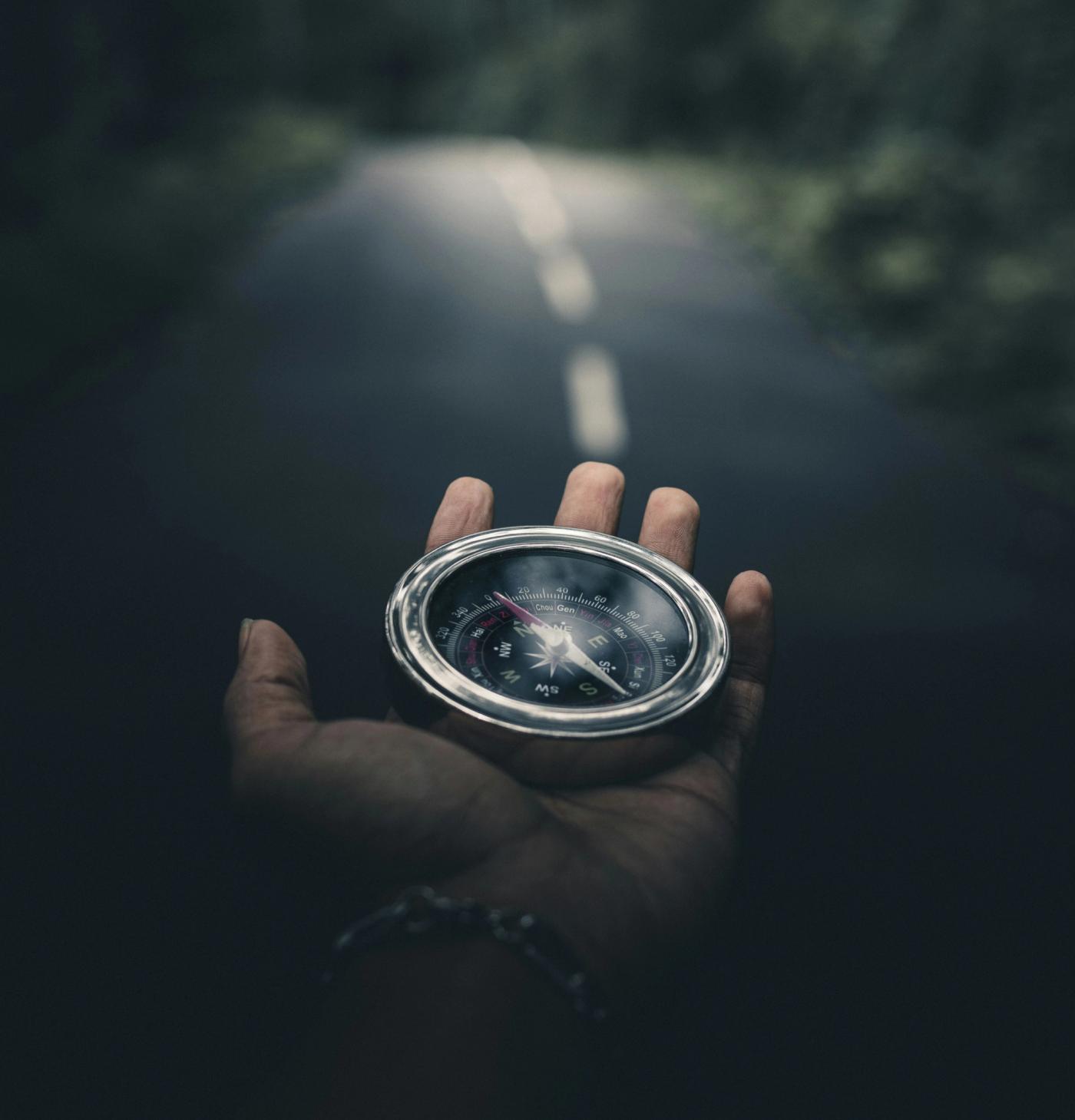 A hand holding a compass searching for the right way to proceed.