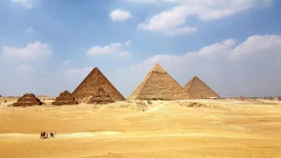 The Pyramids of Giza in a vast desert landscape under a blue sky.