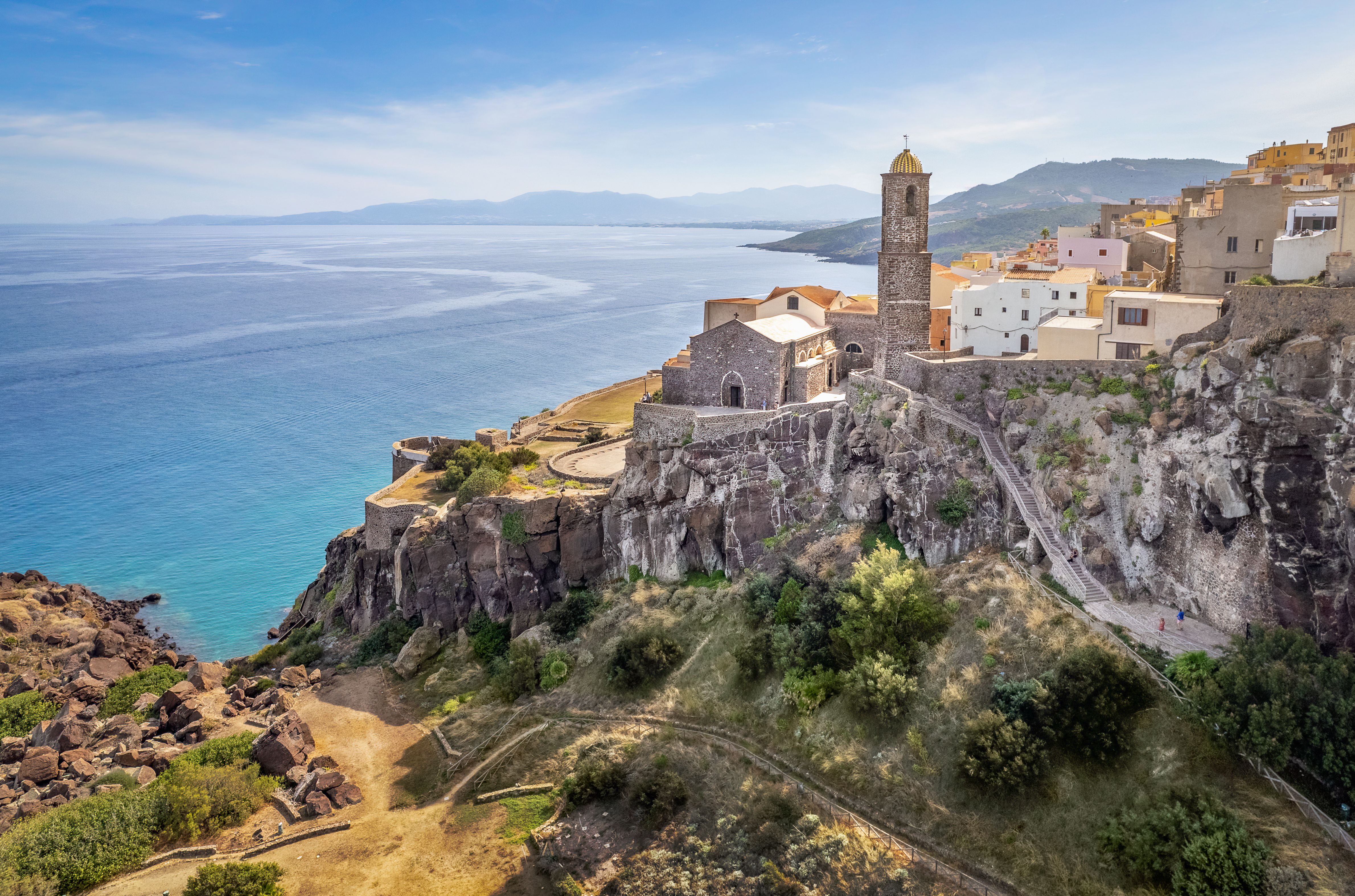 Coastal town on cliffs with a church and bell tower overlooking the sea.